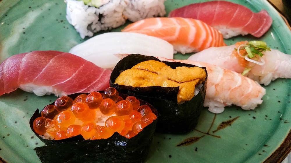 Nigiri on a green plate: tuna, salmon, uni, ikura and shrimp